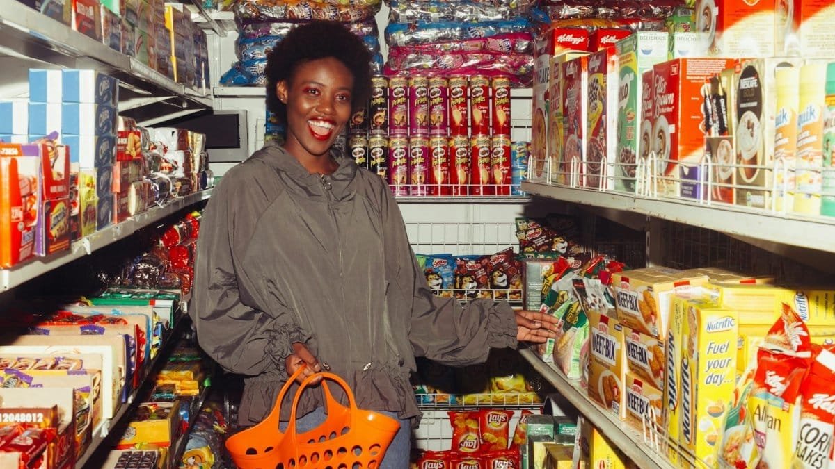 Smiling woman shopping in a grocery aisle filled with colorful products.