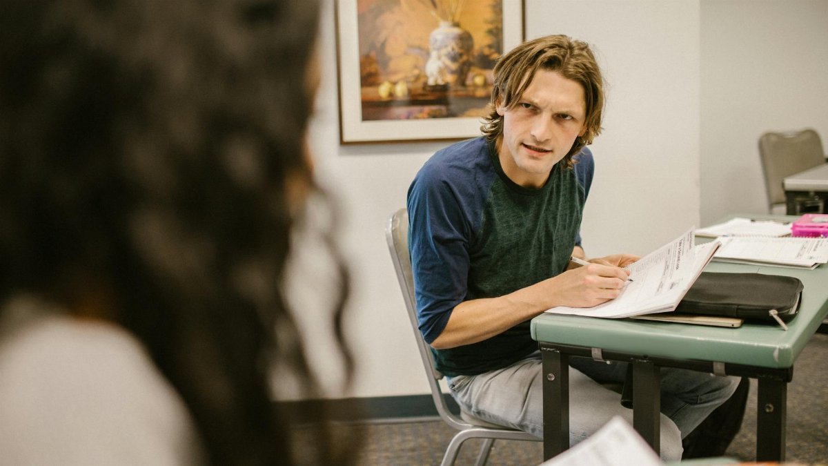 Students engaging in discussion during an exam in a classroom, conveying themes of education and collaboration.