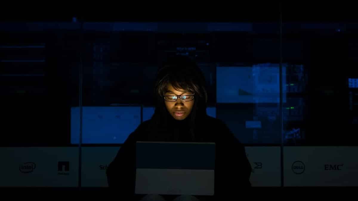 A woman deeply engrossed in programming on a laptop at night in a data center.