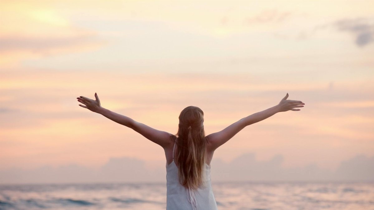 A woman enjoying a serene sunset on Unawatuna Beach, Sri Lanka, depicting peace and freedom.