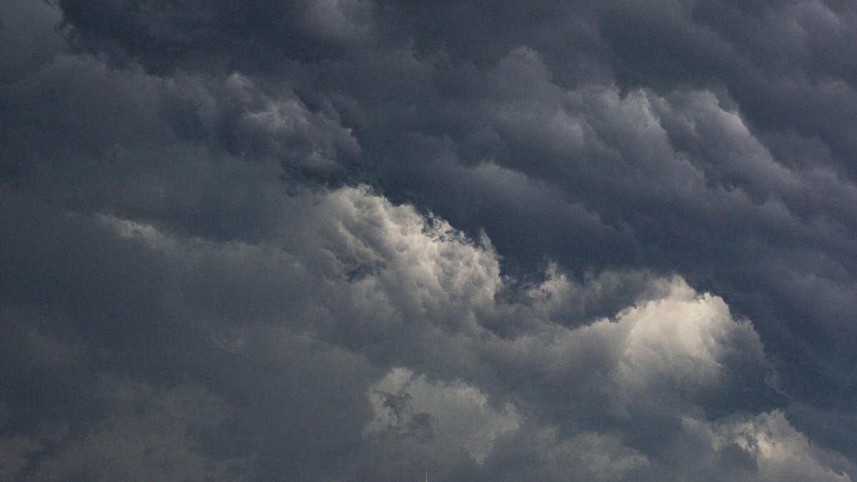 Dark storm clouds loom over city buildings creating a dramatic urban landscape.