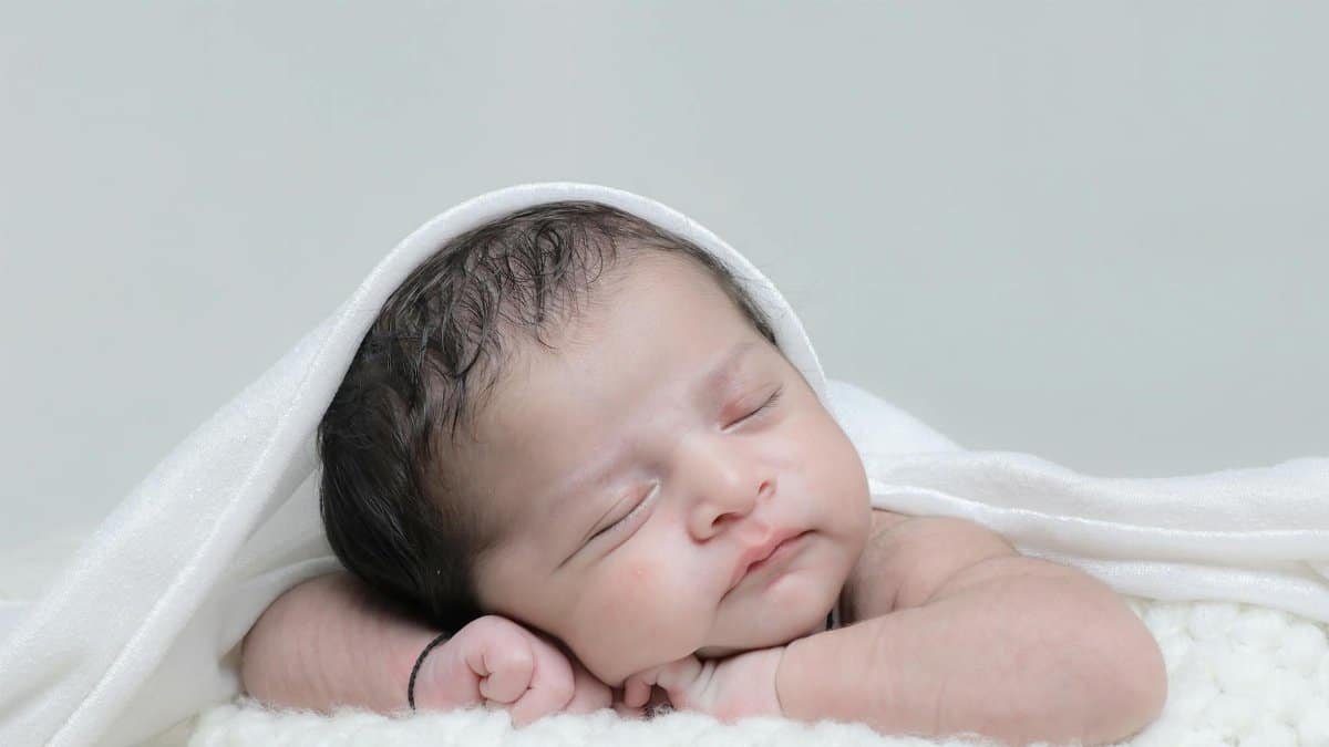 A peaceful newborn baby sleeping, wrapped in a soft white blanket. Perfect for family and parenting themes.