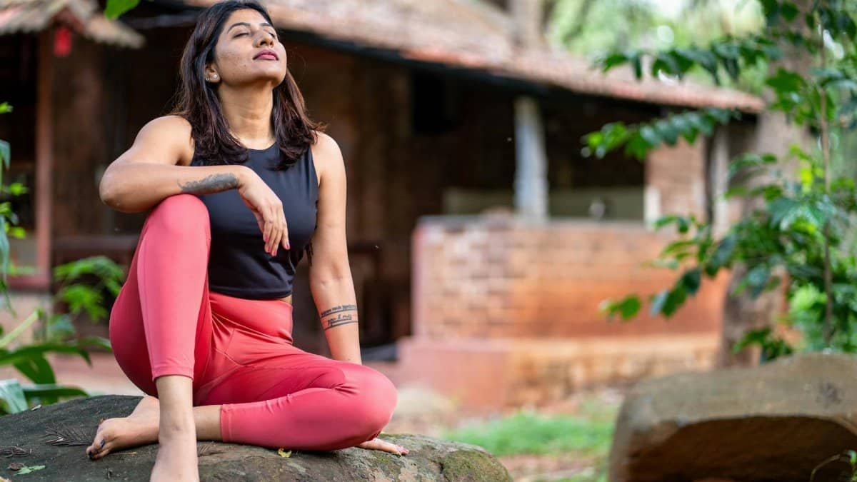 Adult woman practicing meditation on a rock, blending with nature's tranquility.