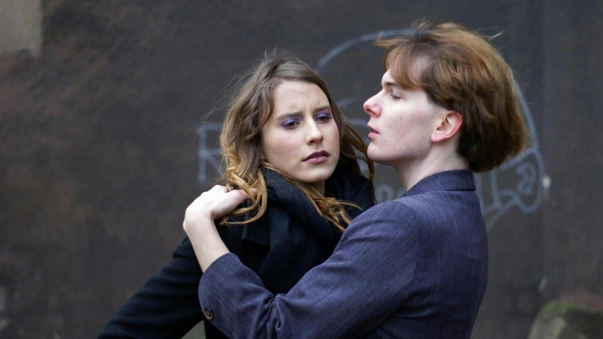 Two young adults in a dramatic outdoor embrace, showcasing emotional intensity and connection.
