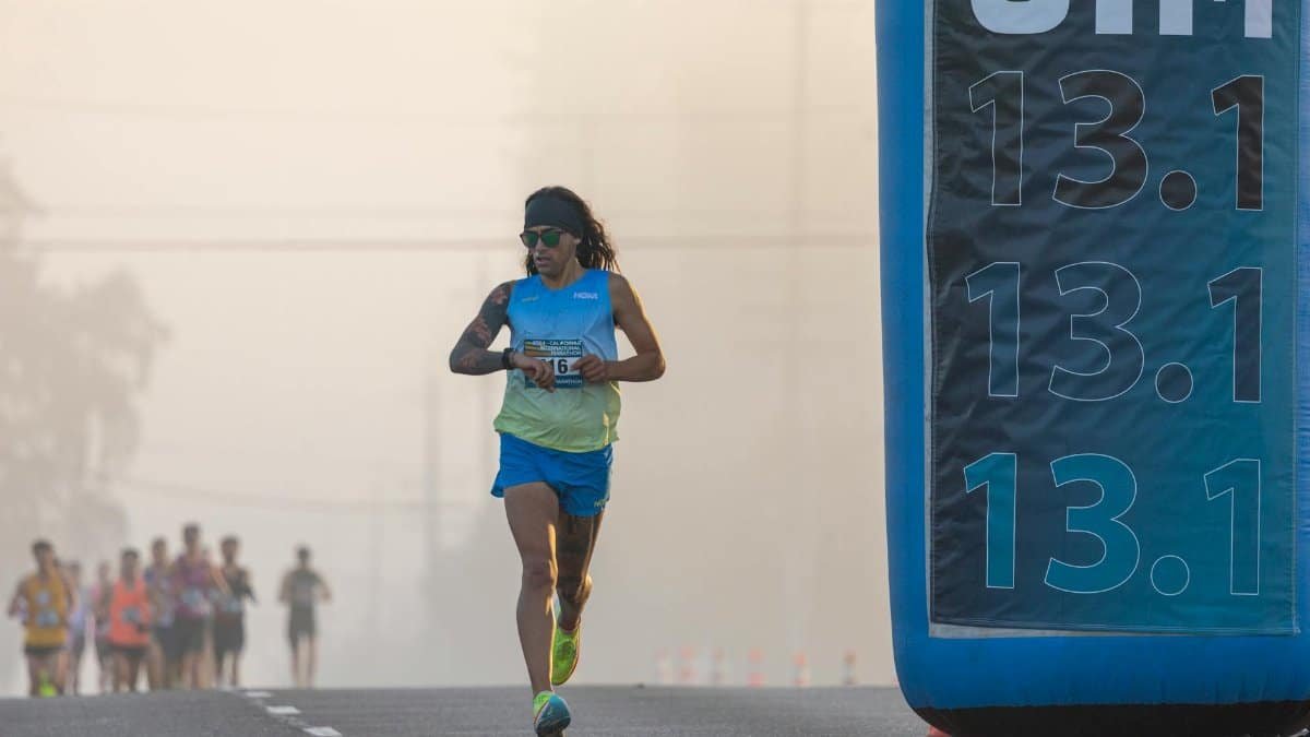 Focused runner at California International Marathon with distance marker in soft light.