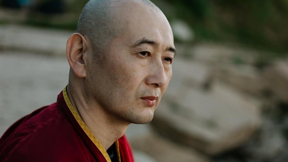 A contemplative bald monk outdoors, captured in a serene moment.