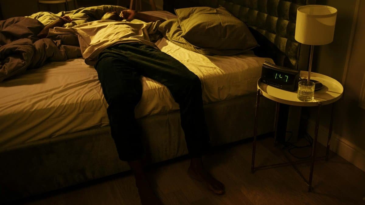 A man lies awake in bed, embodying insomnia and night-time restlessness.