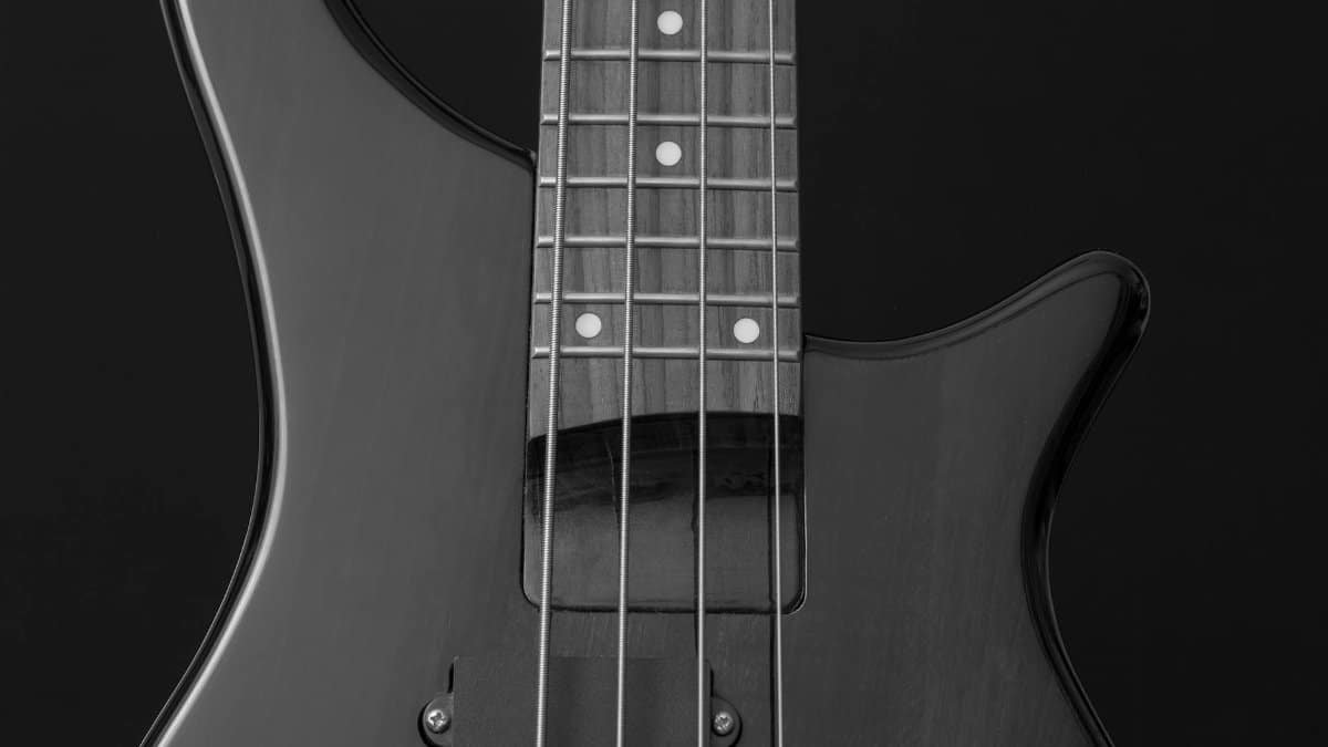Detailed close-up of an electric guitar in black and white, showcasing strings and body.
