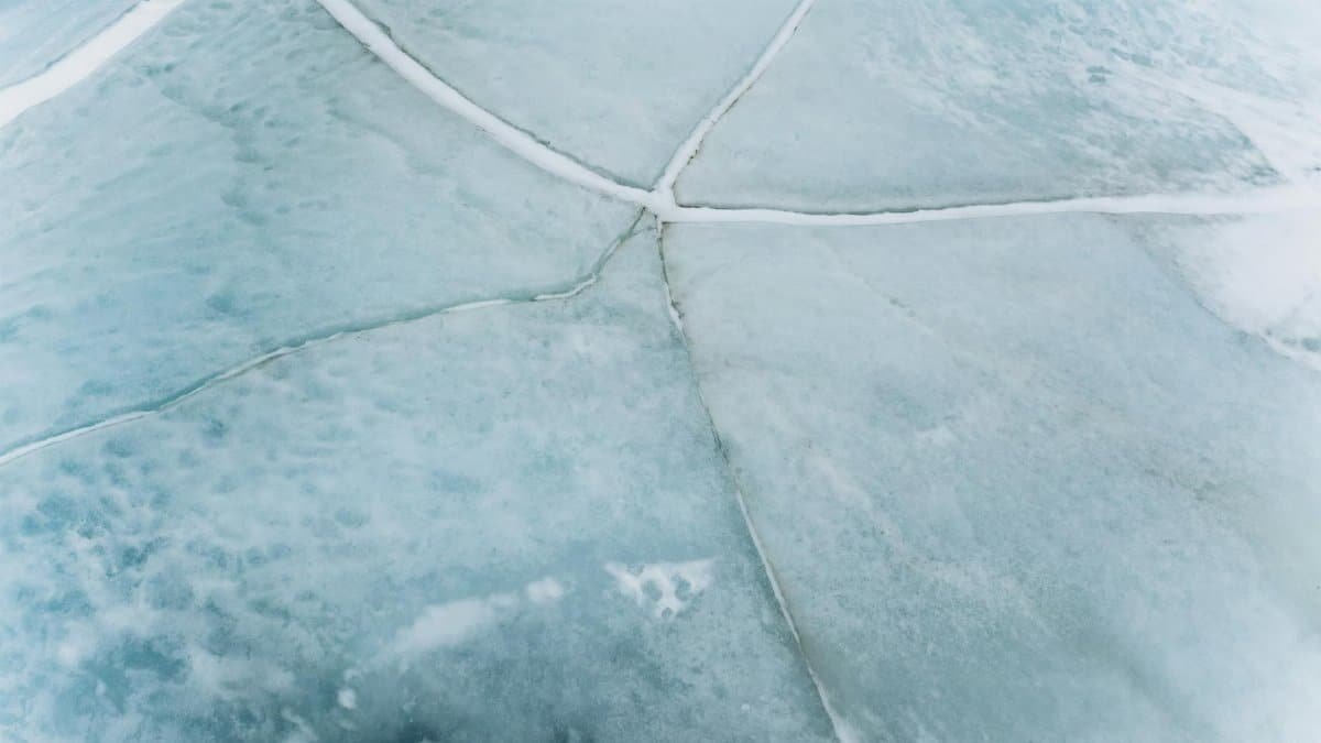 An aerial view of a cracked frozen ice surface in Russia, showcasing intricate natural patterns and winter textures.
