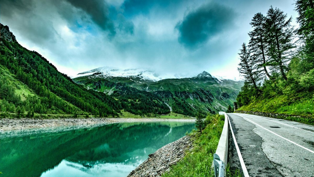 Tranquil mountain landscape featuring a reflective lake and a winding road.