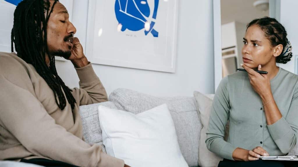 A focused therapy discussion between a male client and female therapist in a serene office.