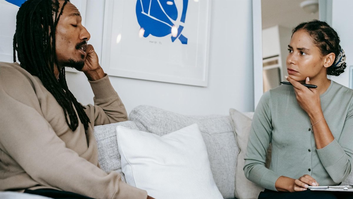 A focused therapy discussion between a male client and female therapist in a serene office.
