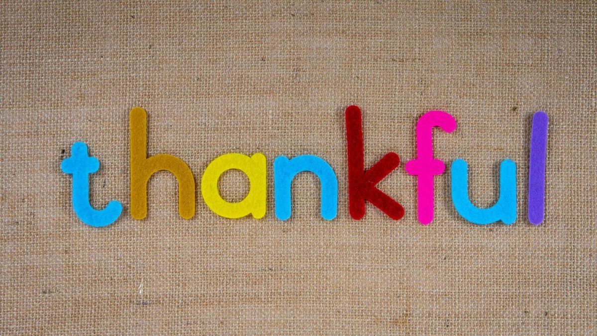 Colorful letters spelling "thankful" on a textured burlap surface, emphasizing gratitude.