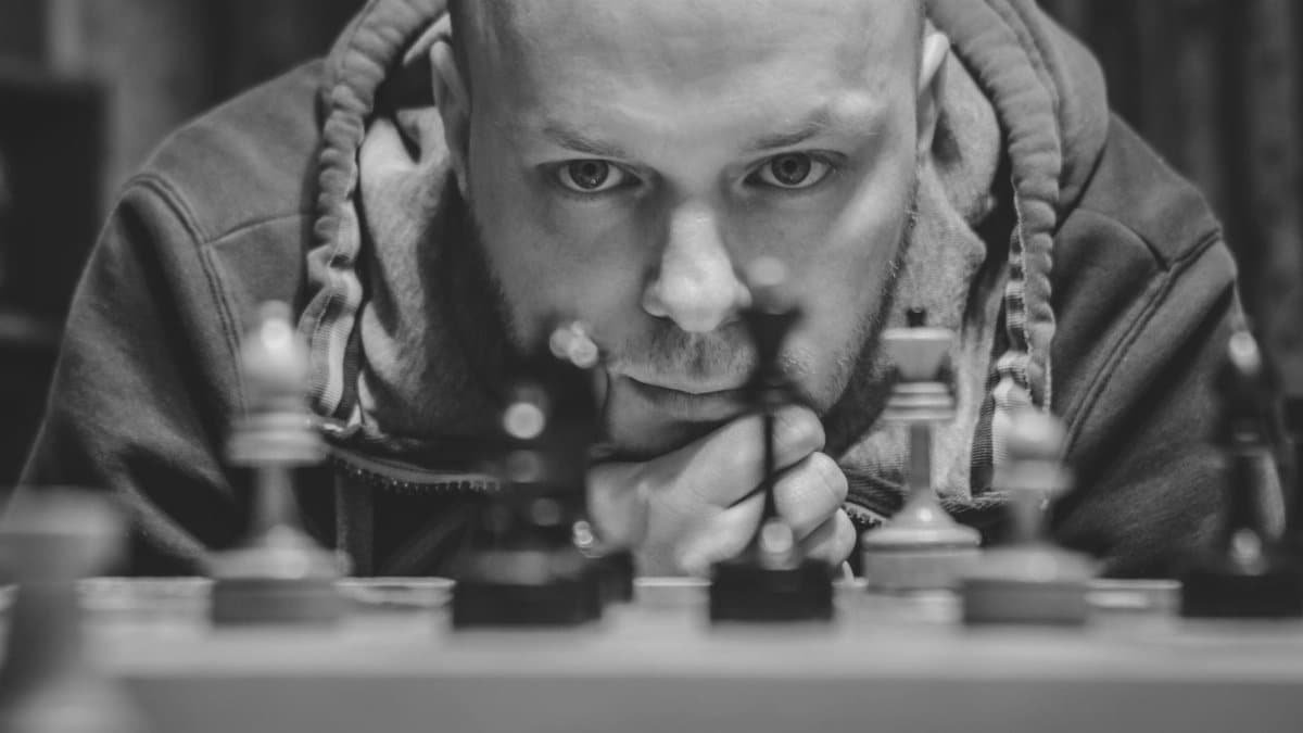 A man intensely focuses on a chess game, contemplating his next move.