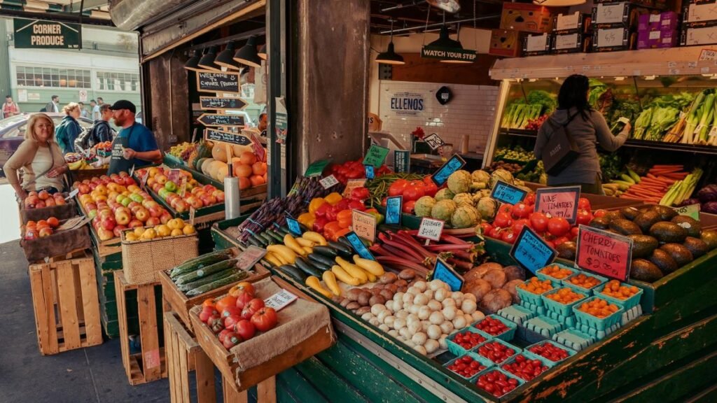 Colorful array of fresh fruits and vegetables at an outdoor farmer's market, with people browsing.