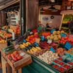 Colorful array of fresh fruits and vegetables at an outdoor farmer's market, with people browsing.
