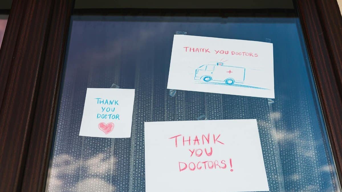 Handwritten notes on a window expressing gratitude towards doctors, featuring colorful drawings.