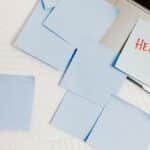 A cluttered workspace with sticky notes on a laptop, symbolizing overwhelm and need for help.