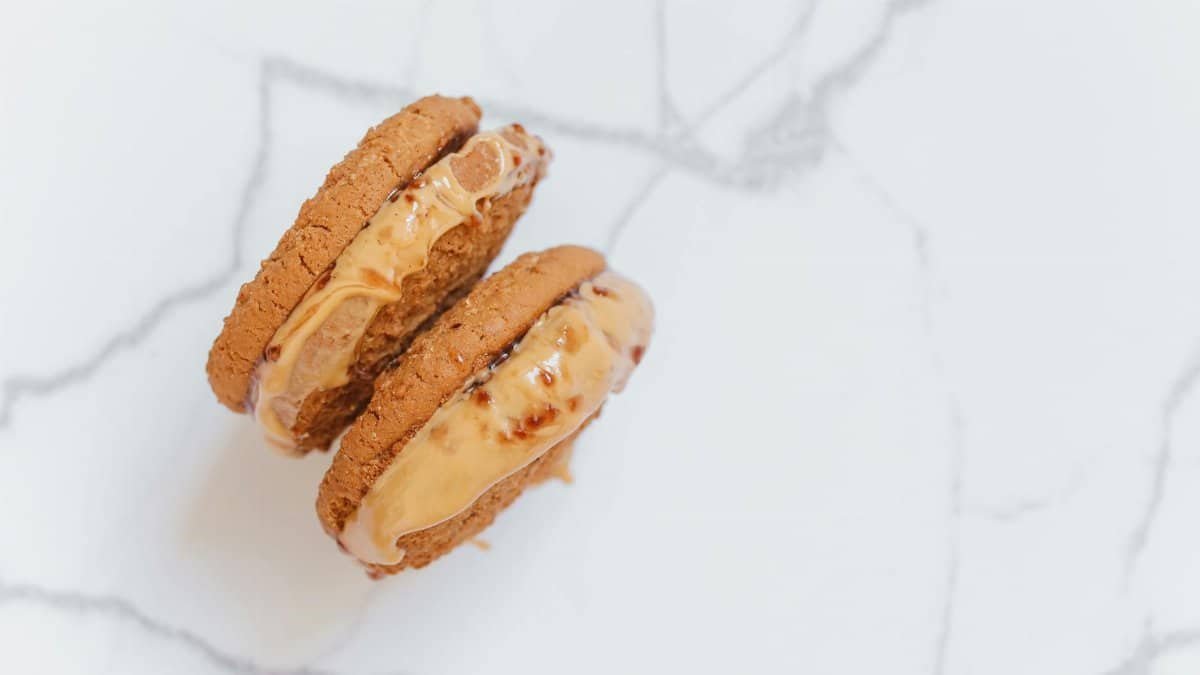 Delicious peanut butter-filled cookie sandwich on a marble surface, showcasing creamy indulgence.