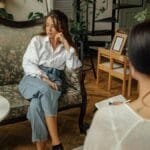 A thoughtful counseling session between a psychologist and a patient in a cozy, well-decorated room.