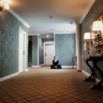 A woman sits peacefully in a luxurious hallway with elegant lamps and decor.