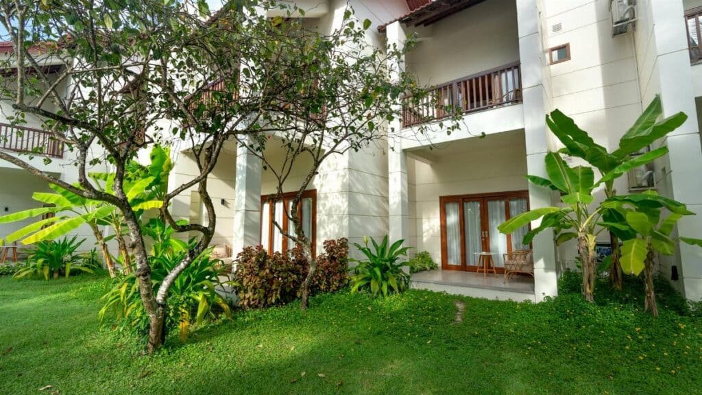 Elegant villa exterior with lush lawn and tropical plants in a summer setting.
