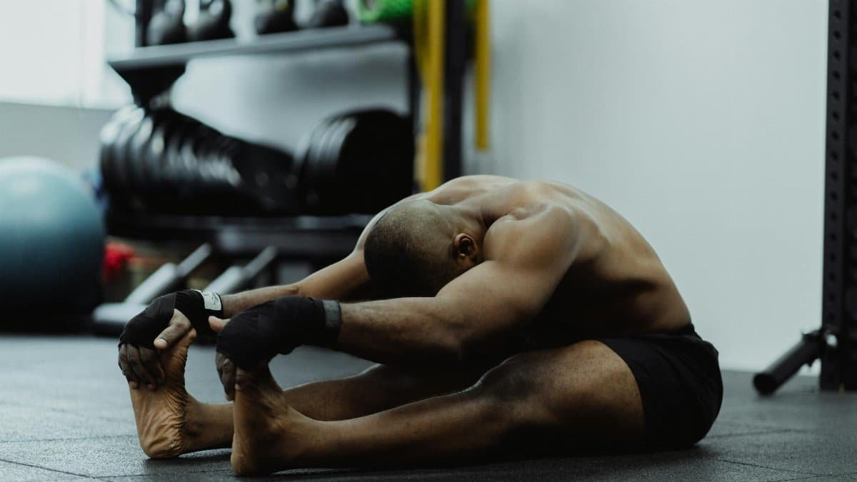 Man doing seated stretch in gym, emphasizing fitness and flexibility training.