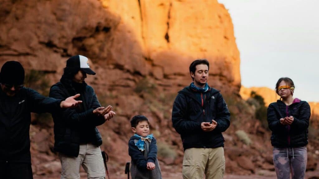 A diverse group meditates in the tranquil desert sunrise, embracing peaceful reflection.