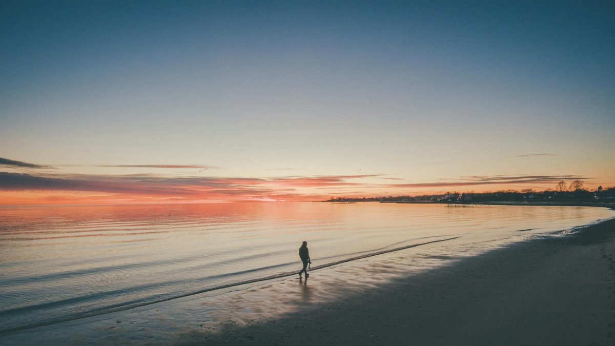 A solitary walk on a tranquil beach with a breathtaking sunset sky.