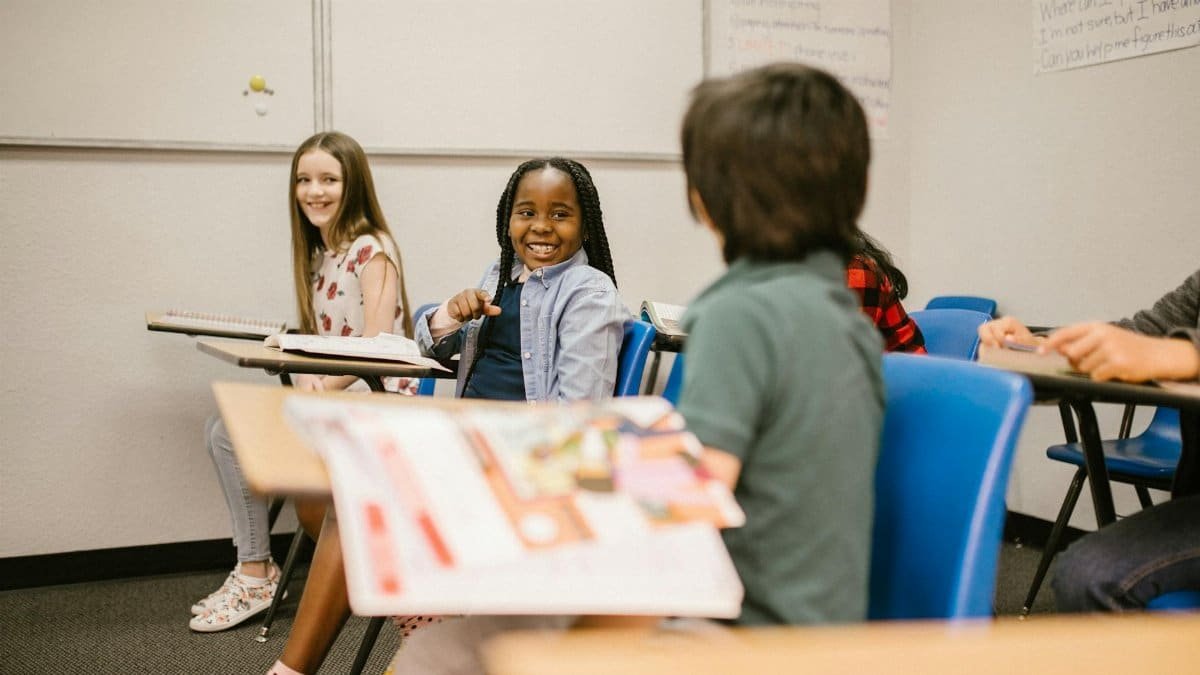 Group of diverse children smiling and engaging in a classroom setting.