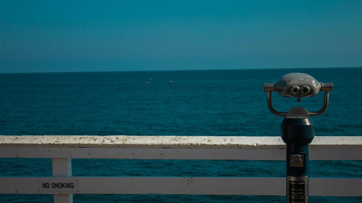 Ocean view from Miami Beach pier featuring binoculars and calm blue waters.