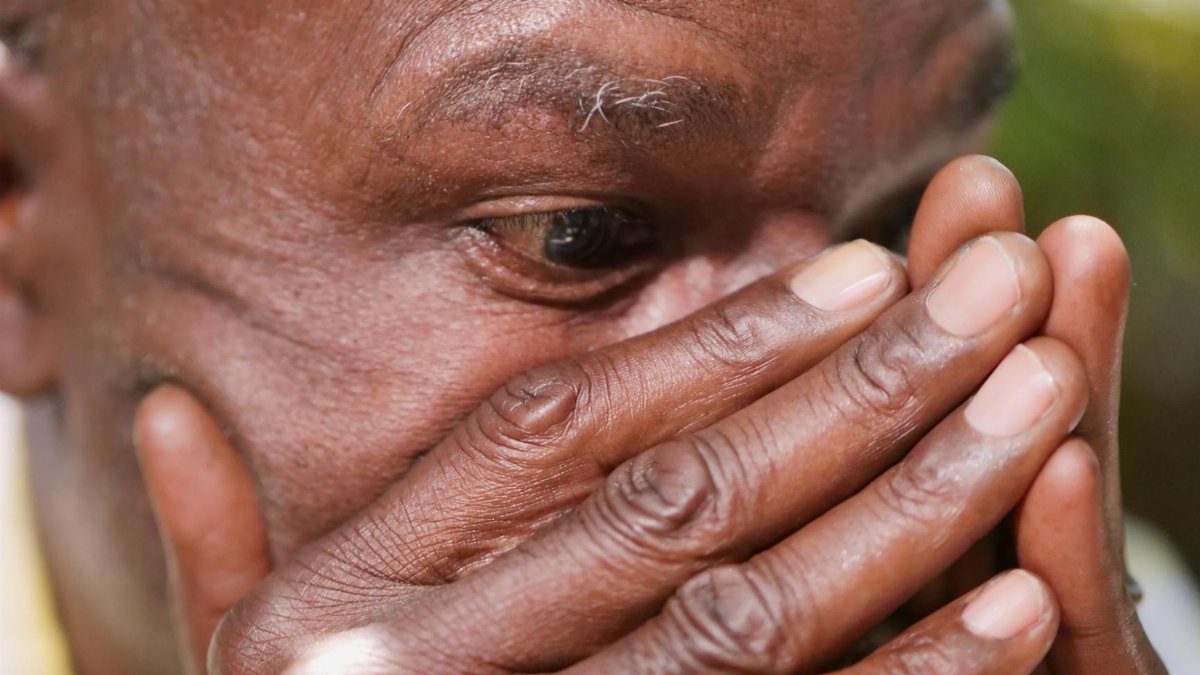 Close-up of a man covering his face with hands in a moment of grief or despair.