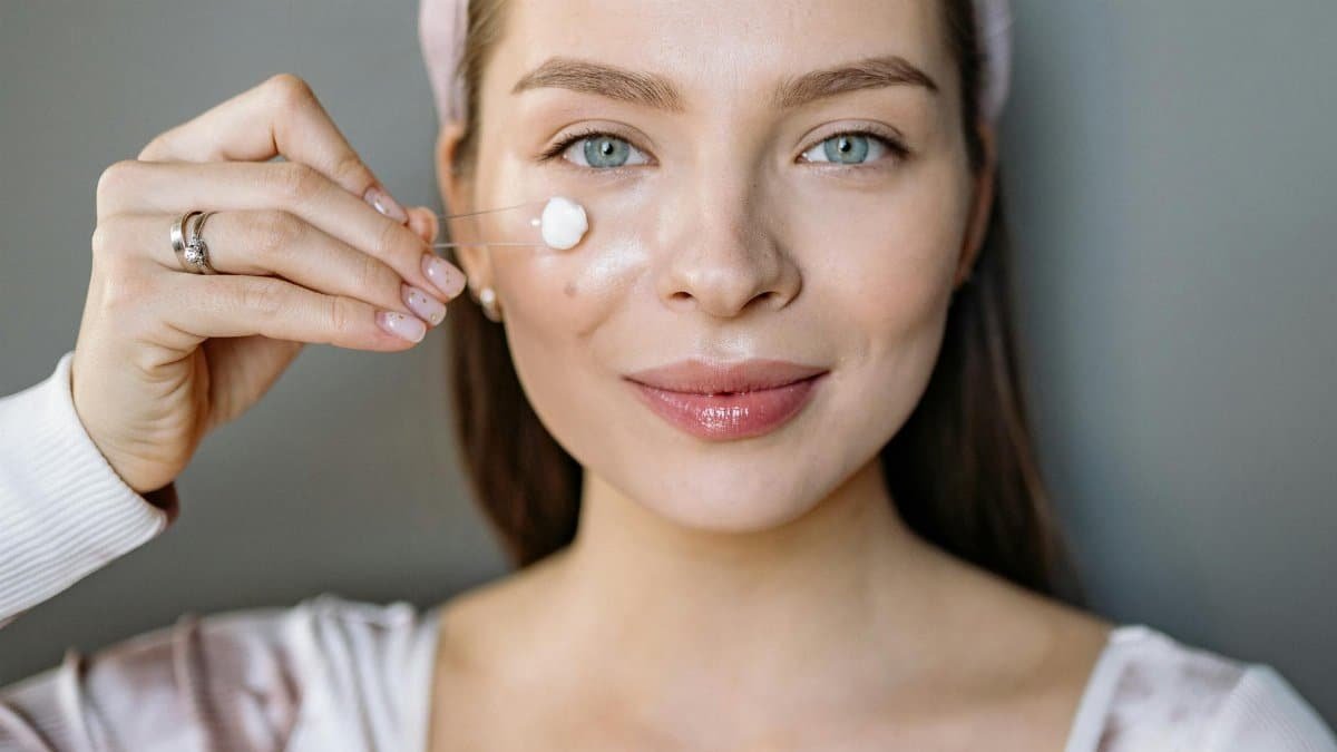 Smiling woman applying facial cream for skincare routine