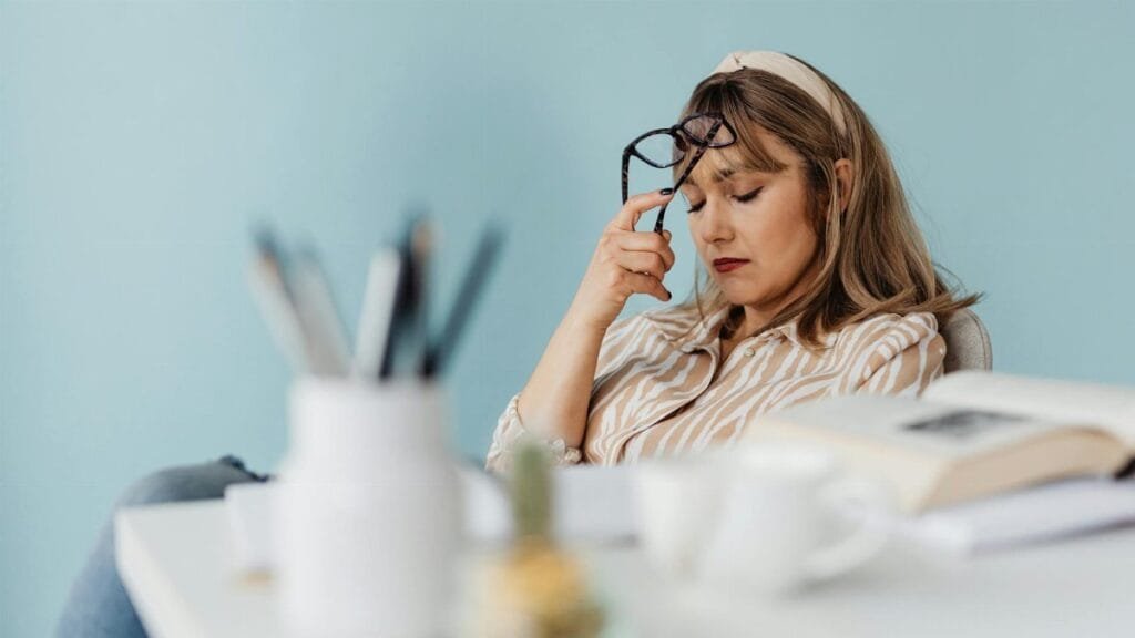 Caucasian woman looks exhausted while taking a break with eyes closed at her desk.