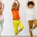 Three diverse children practicing yoga indoors, showcasing joy and balance.