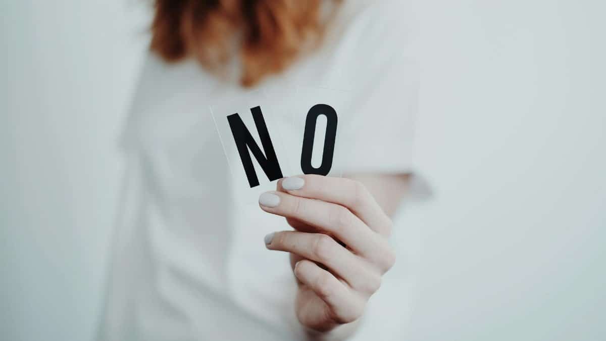 Close-up of a person holding a "No" sign, symbolizing rejection or disagreement.
