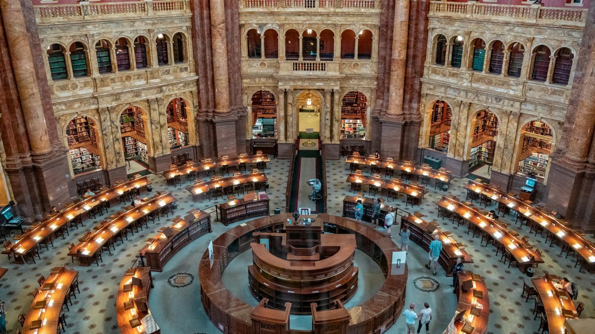Aerial view of the historic Library of Congress reading room with people and beautiful architecture.
