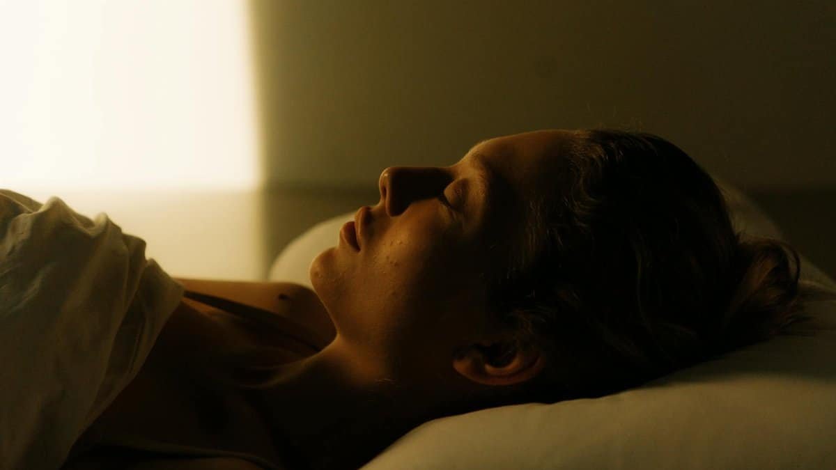 A calming scene of a woman lying in bed, peacefully asleep, bathed in warm light.