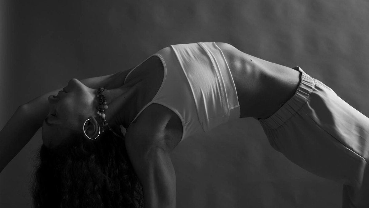 Monochrome image of a woman practicing yoga in a studio setting, emphasizing mindfulness and wellness.