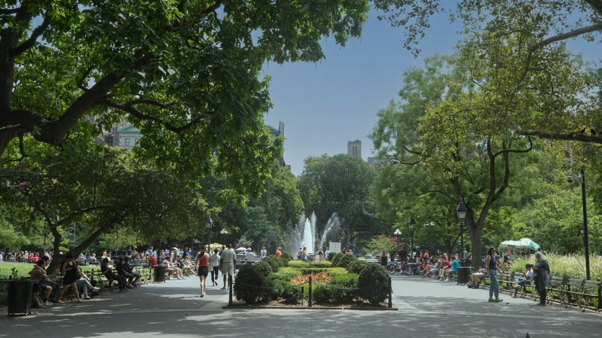 People enjoy a sunny day at Washington Square Park in New York City, surrounded by lush greenery.