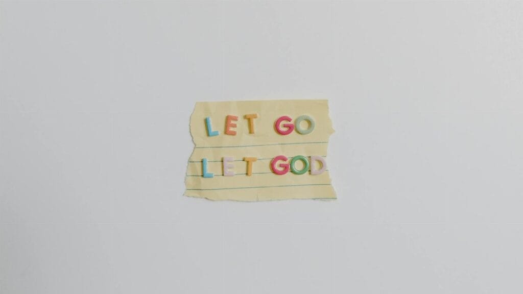 Minimalist image of a torn paper with the phrase 'Let Go, Let God' in colorful letters.