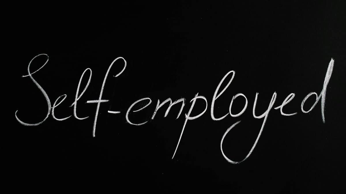 Handwritten 'Self-employed' in chalk on a blackboard background for business concepts.
