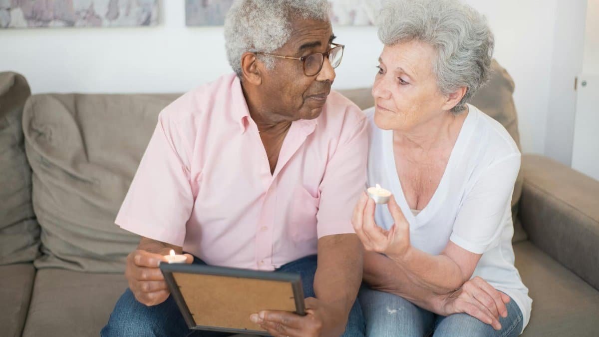A senior couple sharing a heartfelt moment with a picture frame and candles, reflecting on memories together.