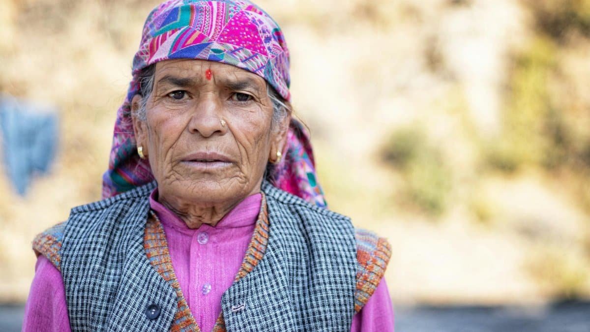 Close-up portrait of an elderly woman wearing a colorful headscarf outdoors.