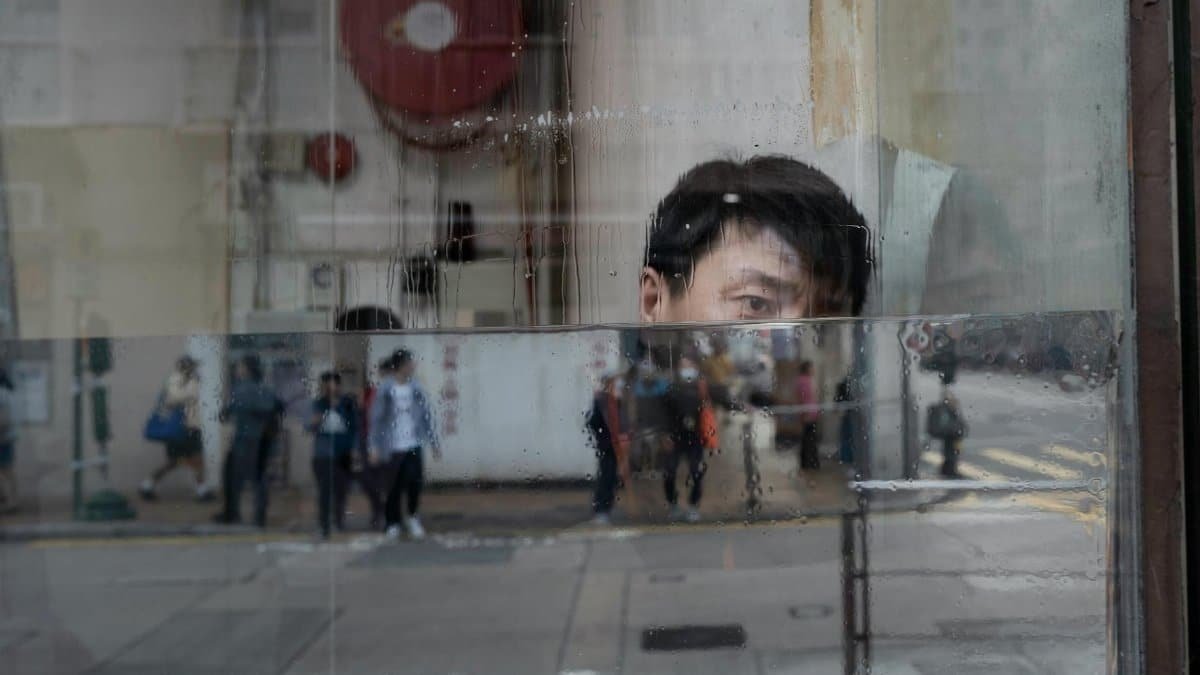 Reflections of people and an individual in a rainy urban setting.