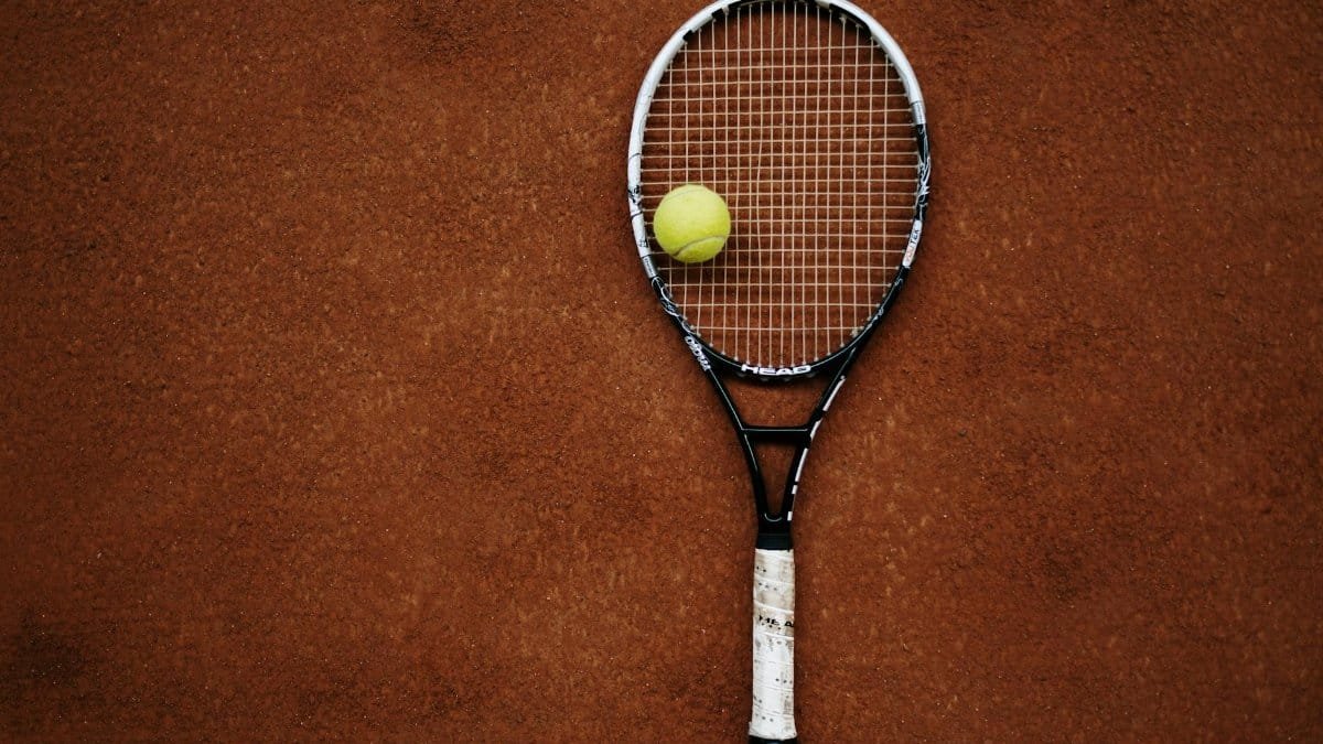 Tennis racket and ball on clay court, perfect for sports imagery.