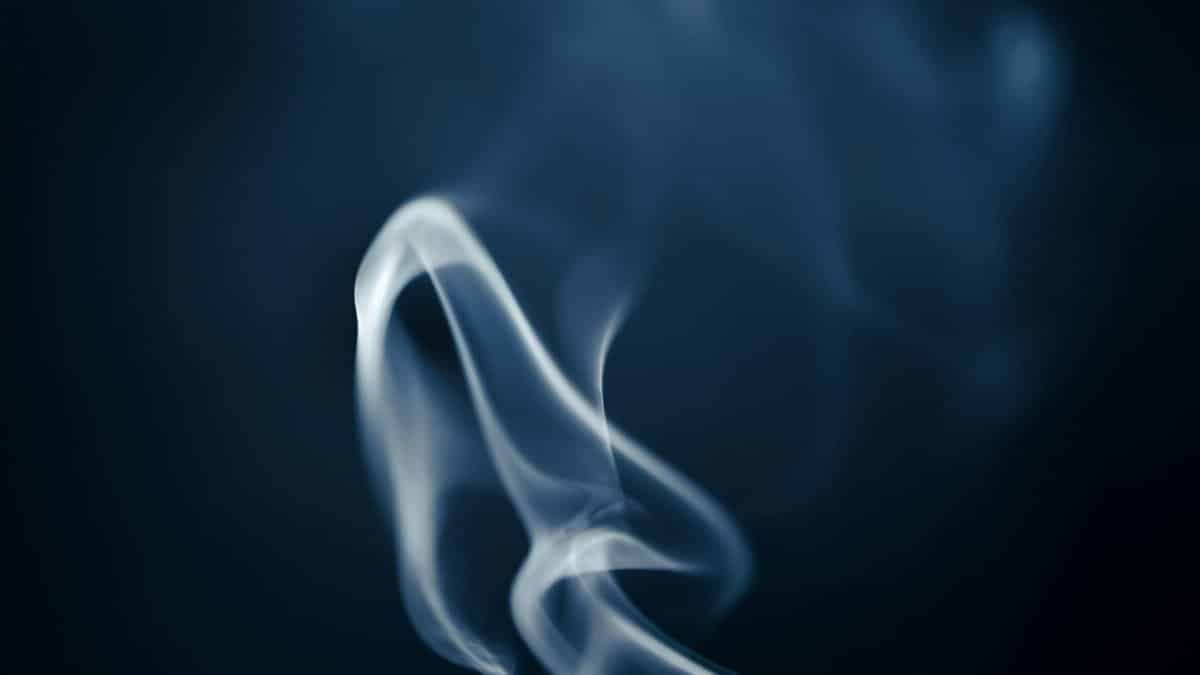 Artistic image of smoke swirling gracefully in contrast to a dark backdrop.