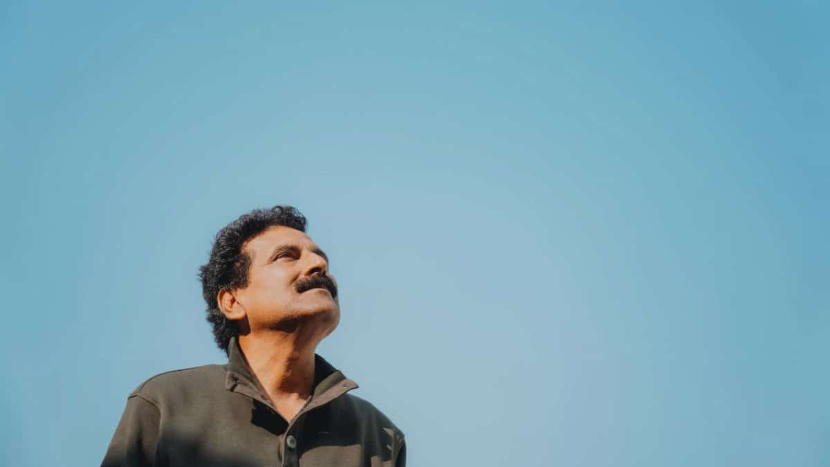 Portrait of a man with a mustache looking up at a bright, clear sky. Ideal for themes of contemplation and serenity.