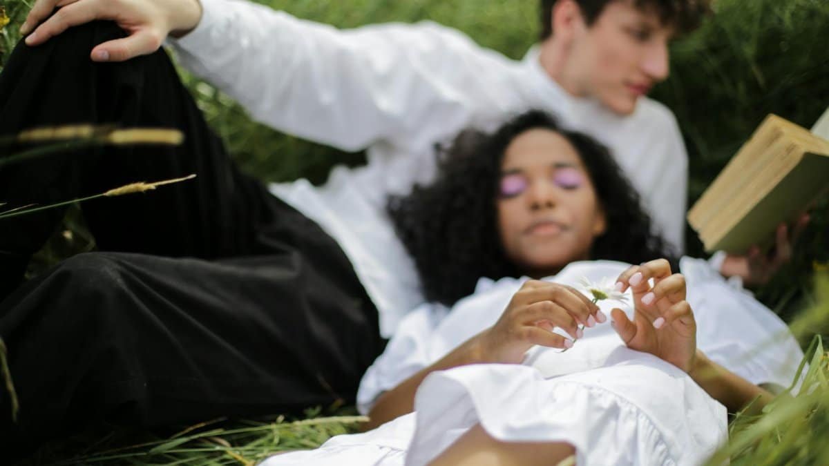 Couple relaxing in a meadow, enjoying summer nature, love, and tranquility.