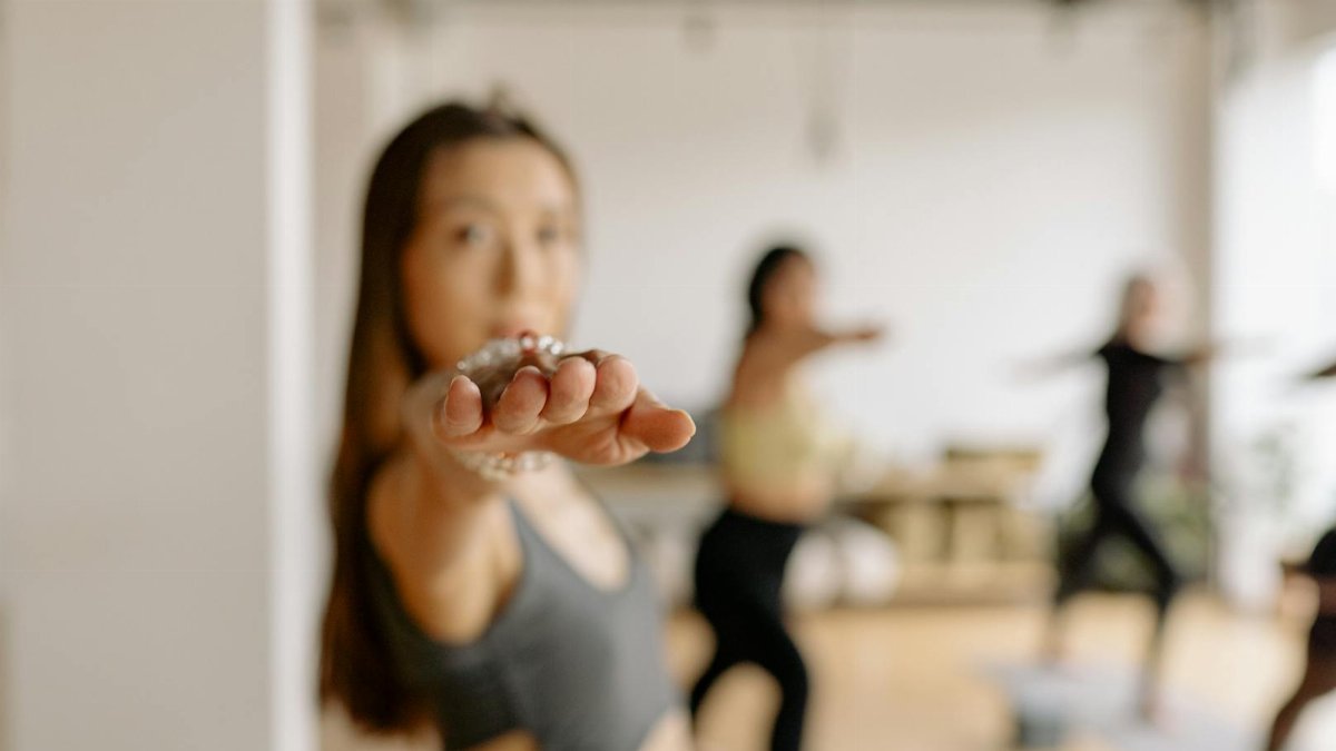 Women practicing warrior pose in a yoga class. Focused and serene atmosphere.